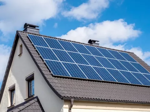 Toiture d’une maison équipée de panneaux photovoltaïques sous un ciel bleu, photo de l’article ADEME sur le stockage virtuel.