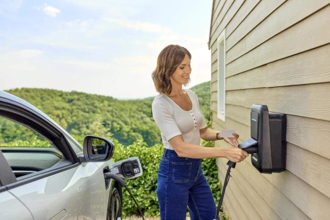 Une conductrice utilise la borne Hager witty one sur le mur de sa maison