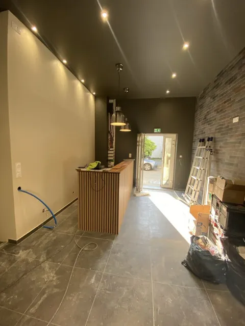 Éclairage par spots au plafond d’une pièce avec un mur en pierre et des rangements en bois