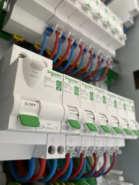 Vue rapprochée de disjoncteurs et de leurs raccordements électriques rouges et bleus