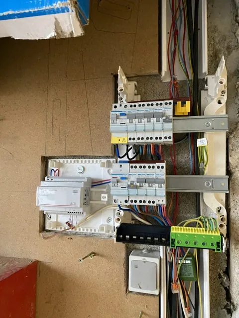 Disjoncteurs et fils d’un petit tableau électrique sur un support en contreplaqué