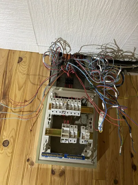 Tableau électrique ouvert et câbles apparents pendant une rénovation