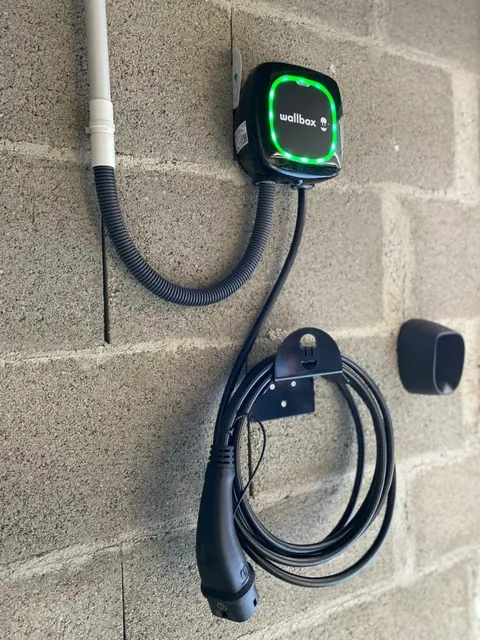 Borne Wallbox sur un mur en parpaings avec son câble de recharge enroulé en dessous
