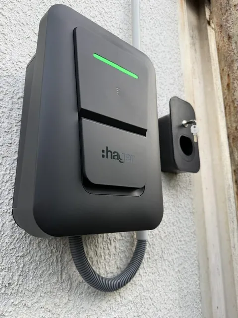 Borne Hager murale au voyant vert et prise électrique sur un mur extérieur