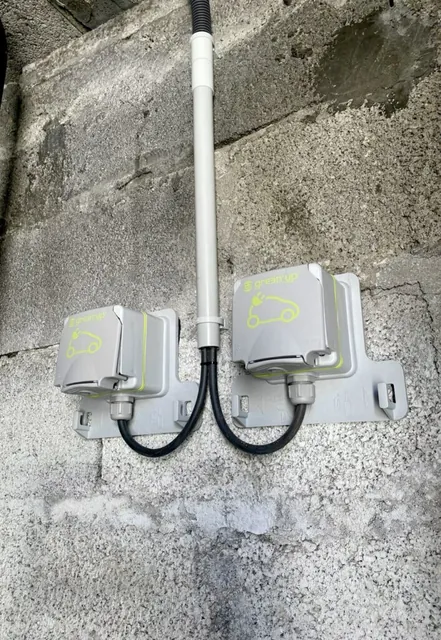Coffrets de protection et conduits électriques à côté d’une borne de recharge extérieure