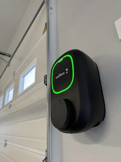 Borne Wallbox au voyant vert installée dans un garage aux murs blancs