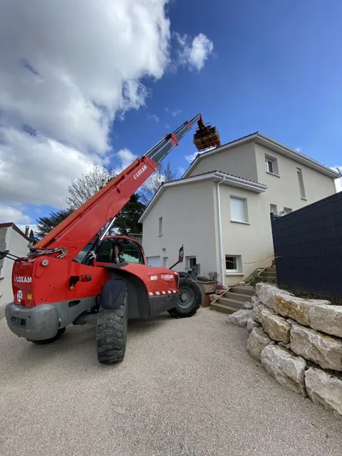 Engin de levage rouge devant une maison pendant le chantier solaire