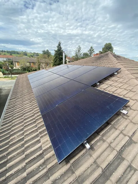 Vue d’ensemble de panneaux photovoltaïques sur une toiture sous un ciel nuageux