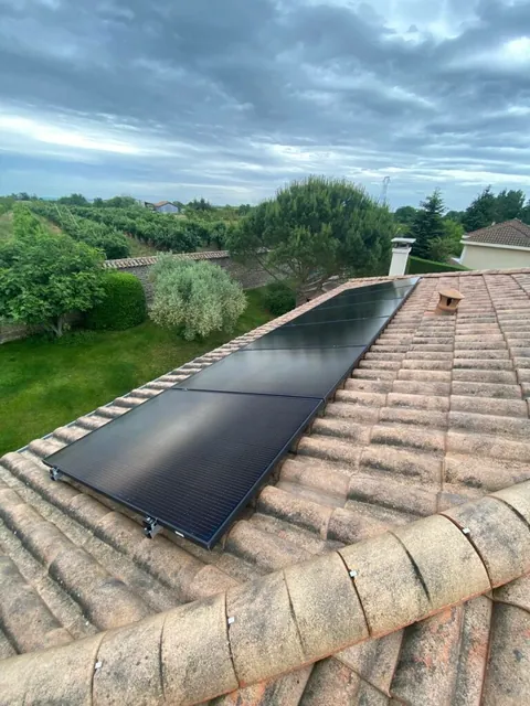 Autre vue d’une rangée de panneaux photovoltaïques depuis le bord d’une toiture en tuiles