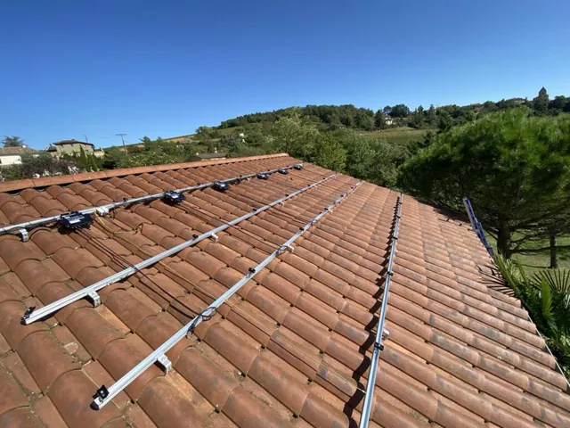 Ensemble de rails photovoltaïques sur une toiture en tuiles avec la campagne en arrière-plan