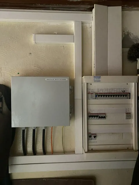 Onduleur blanc et tableau de protection électrique posés côte à côte sur un mur