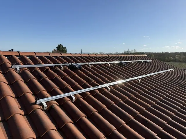 Rails de fixation disposés sur une toiture en tuiles avant la pose des panneaux solaires