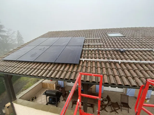 Panneaux photovoltaïques au-dessus d’une terrasse avec un échafaudage en bord de toiture