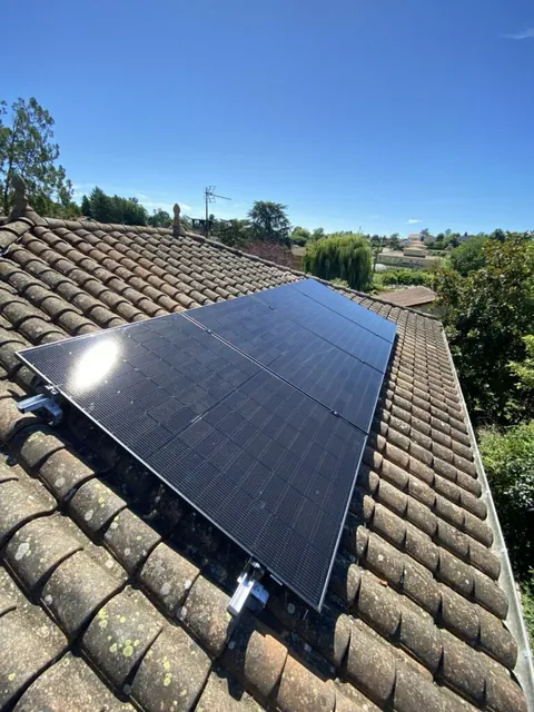 Champ de panneaux solaires sur des tuiles grises avec des reflets sur les modules