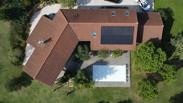 Vue aérienne de deux groupes de panneaux solaires sur une maison avec piscine